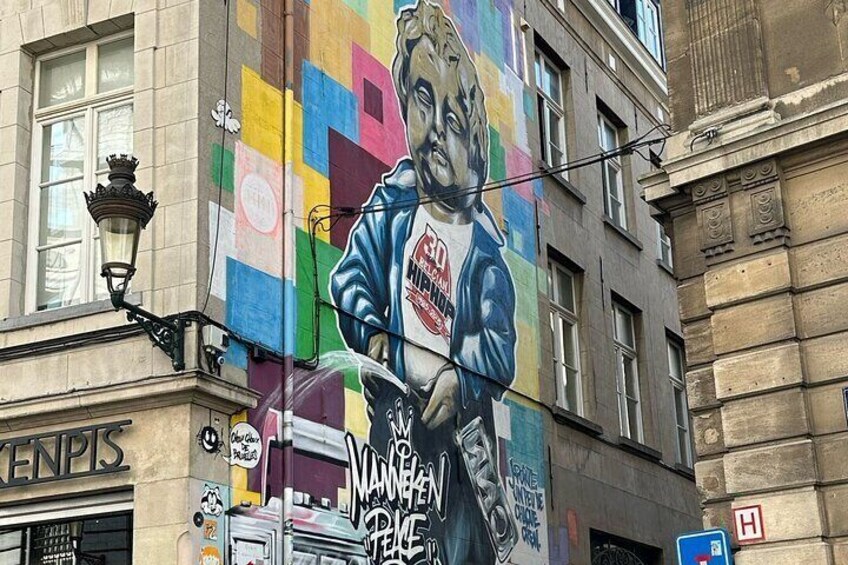 A mural on a building with a person holding a sign that says 'MANGEN FLEISCH.' 3