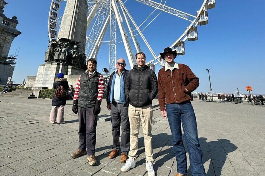 A Ferris wheel, a statue, and people standing in a plaza. 5