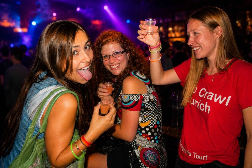Three people at a social event, one holding a drink. 1