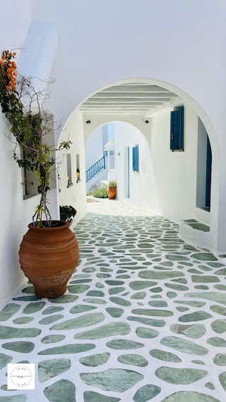 A white-walled corridor with a stone-tiled floor, leading to a staircase. 4