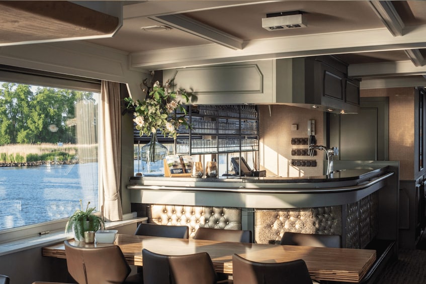 A modern kitchen with a bar area, a dining table with chairs, and a view of a body of water outside. 4