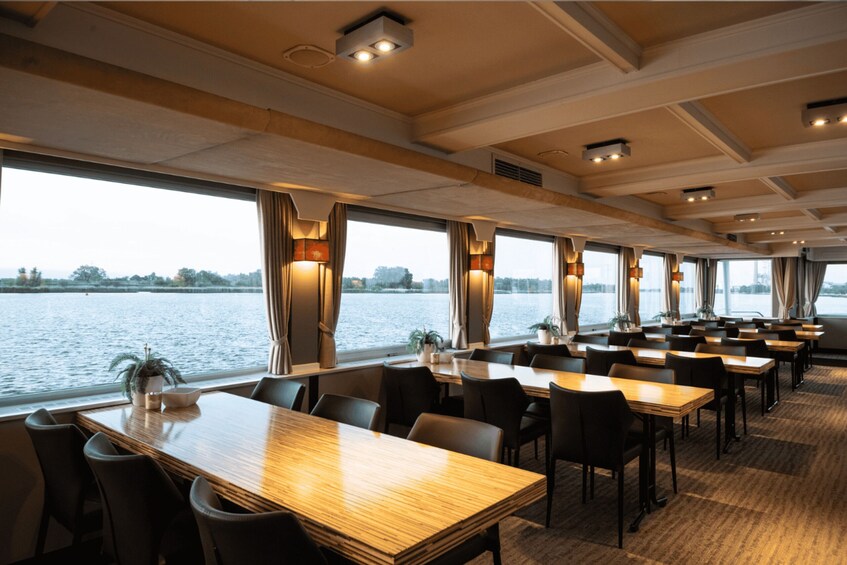 A dining area with tables and chairs, large windows, and a view of a body of water. 5