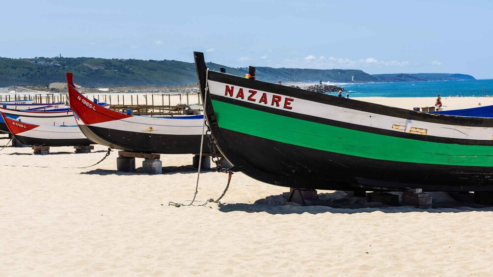 Several boats on a sandy beach with a clear sky and distant hills. 4