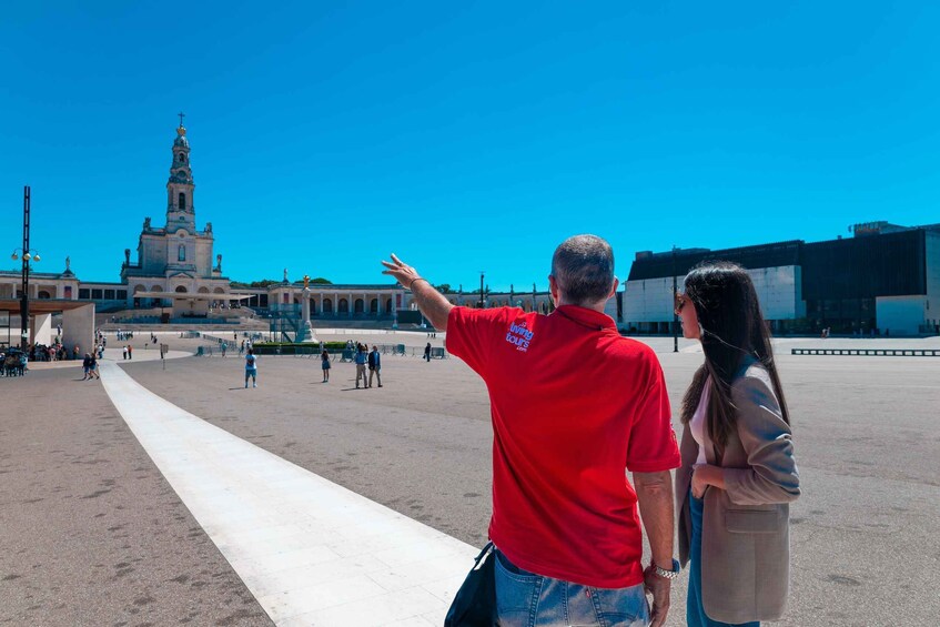 A man pointing towards a historic church with a tall bell tower. 2