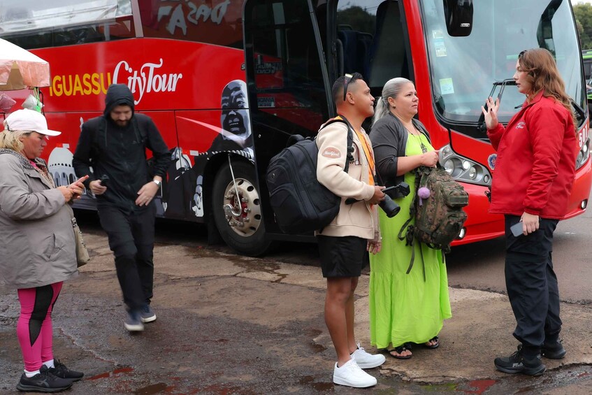 A group of people boarding a red bus with 'GUASSI CityTour' written on it. 5