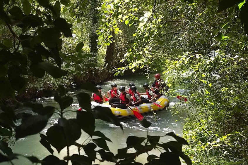 A group of people in a yellow raft navigating a narrow river surrounded by dense greenery. 2
