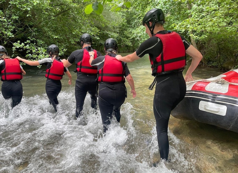 A group of people in life jackets walking through a river. 5