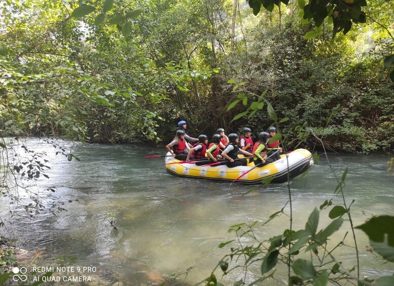 A group of people in a yellow inflatable raft on a river surrounded by dense greenery. 4