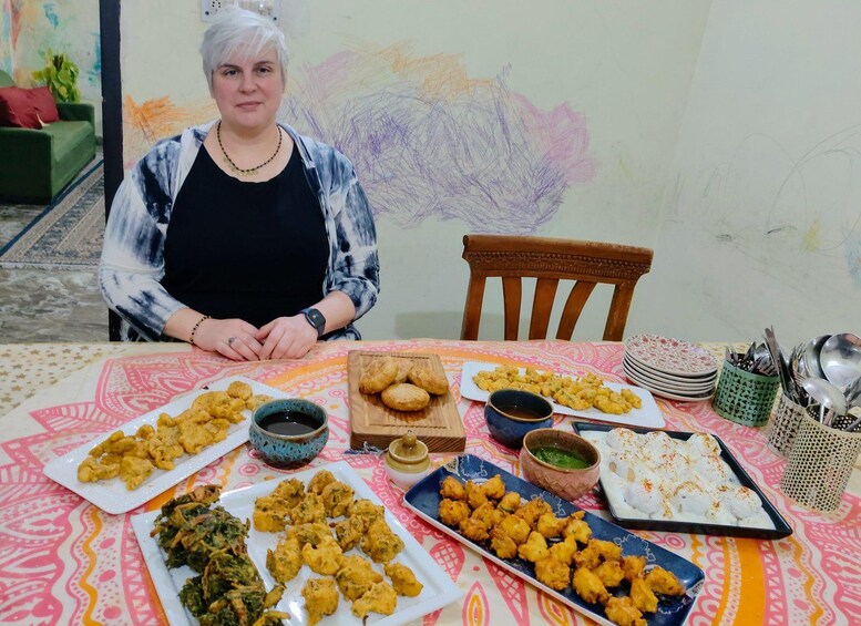 A person seated at a table with various dishes, including fried items and a plate of what appears to be a dessert. 5