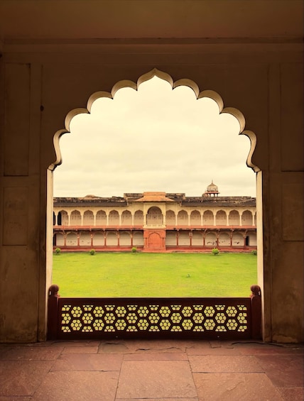 An arched doorway with a view of a courtyard and a building with a dome. 2