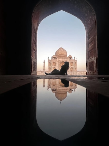 A person sitting in a reflective pool with the Taj Mahal in the background. 1