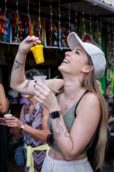 A person holding a yellow cup, wearing a cap, and a green top. 4