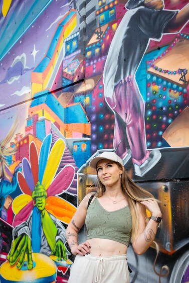 A person standing in front of a colorful mural with a large flower and a figure in a suit. 2