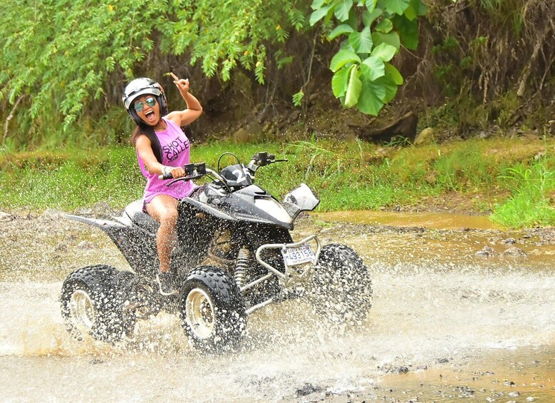 A person riding an ATV through a muddy stream. 5
