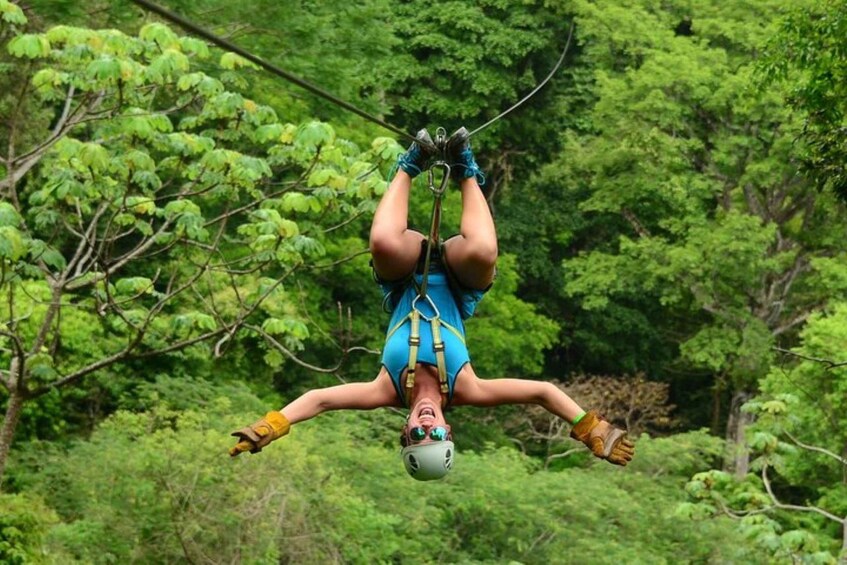 A person bungee jumping with a harness and helmet, surrounded by dense green foliage. 5