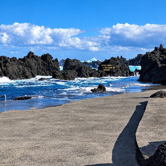 A rocky coastline with waves crashing against the rocks under a clear blue sky. 4