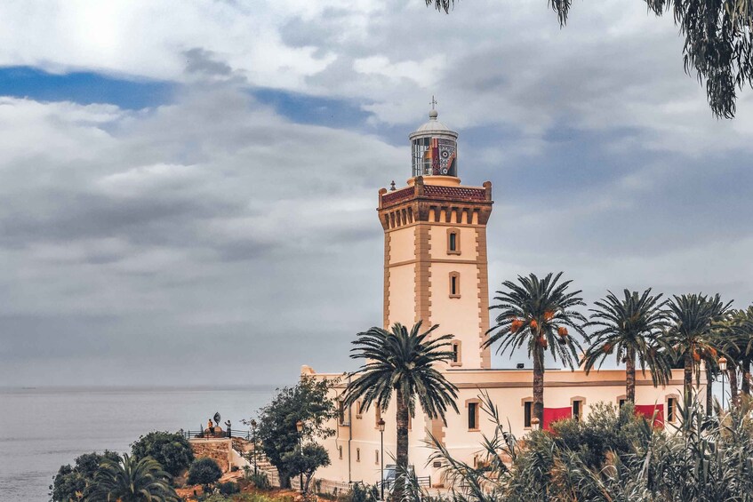 A coastal tower with a dome and a cross on top, surrounded by palm trees and a beach. 1