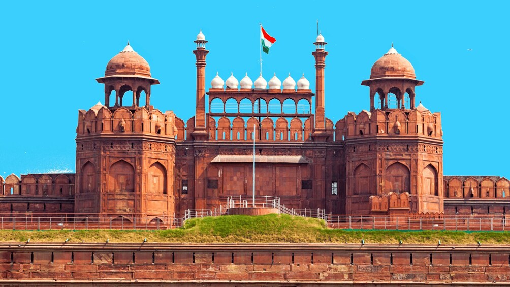 A large, historic building with domes and minarets, a flag, and a clear blue sky. 2