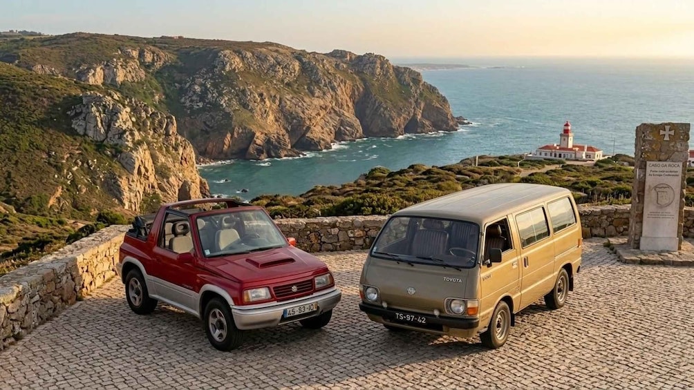 A red and a beige van parked on a cobblestone path with a coastal landscape in the background. 1