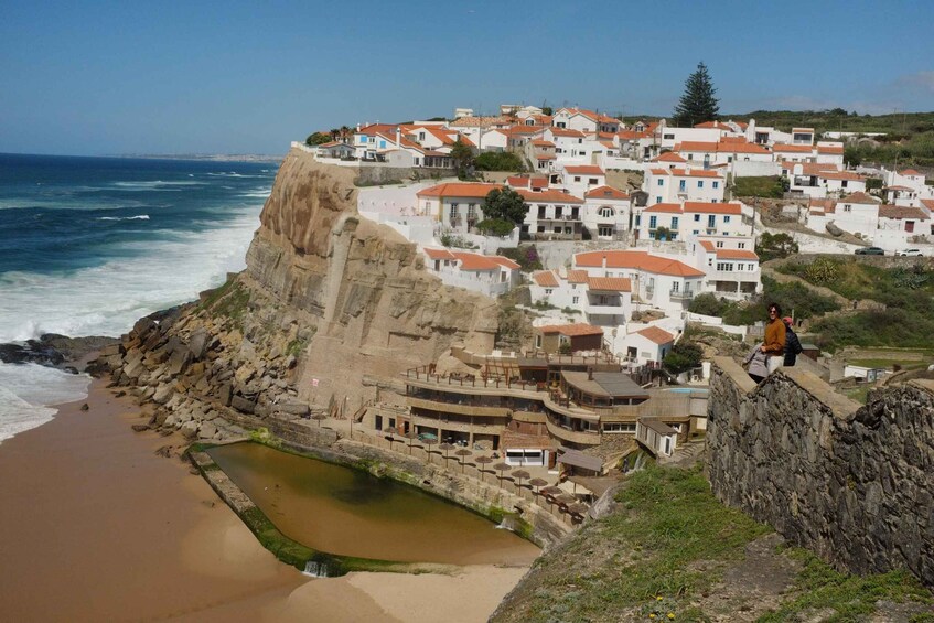 A coastal village with white buildings, a beach, and a rocky cliff. 2
