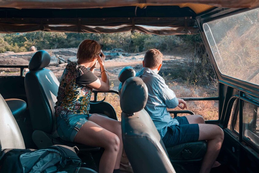 A vehicle interior with passengers looking out at a rocky landscape. 5
