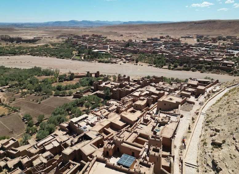 A desert town with adobe buildings, a river, and distant mountains. 5