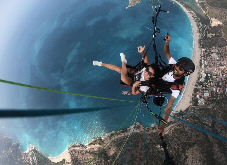A person paragliding over a coastal area with a beach and buildings below. 2
