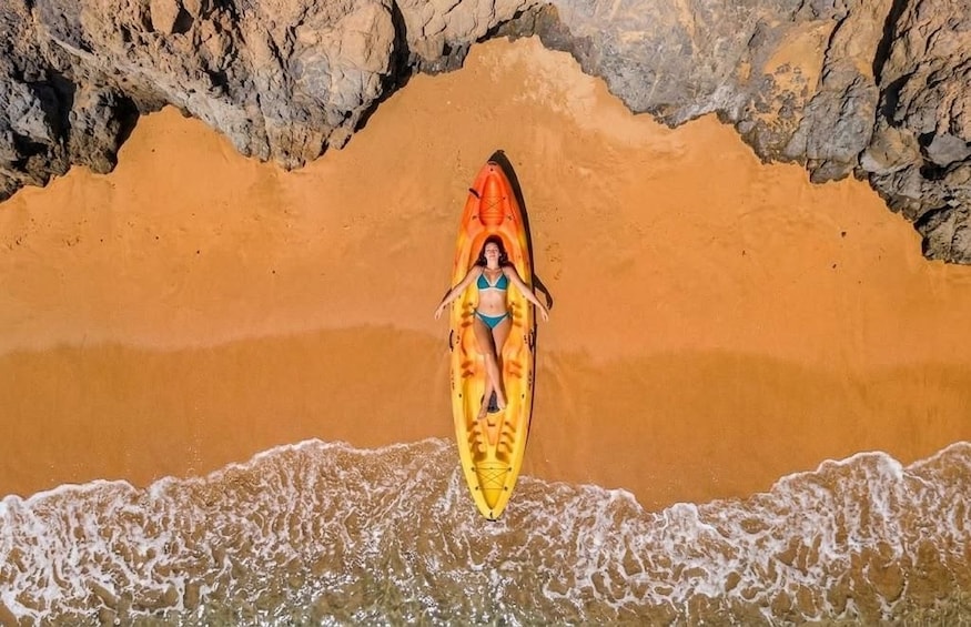 A person in a kayak on a sandy beach with waves. 2