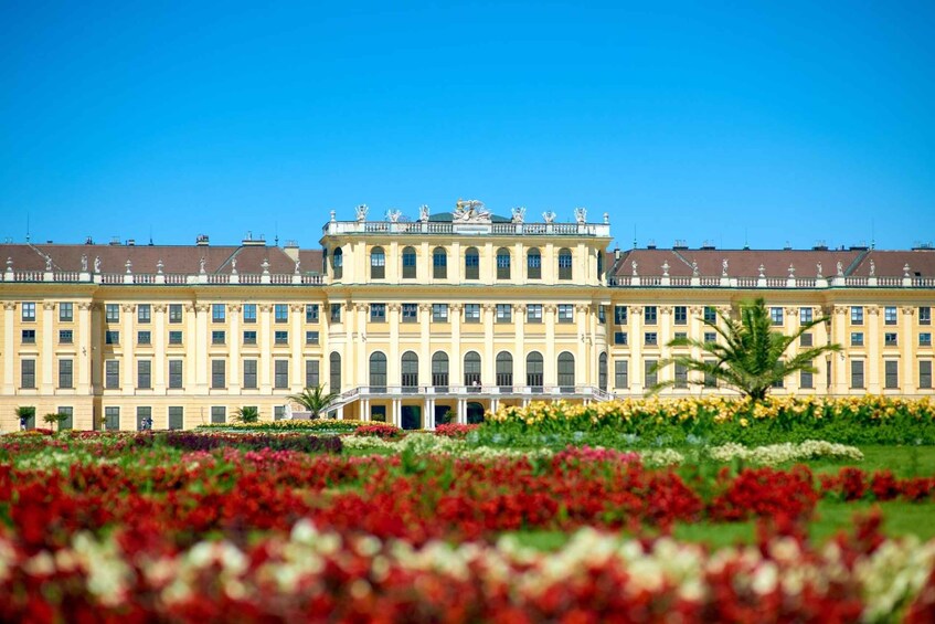 A large classical building with a symmetrical facade, arched windows, and statues on the roof. 4