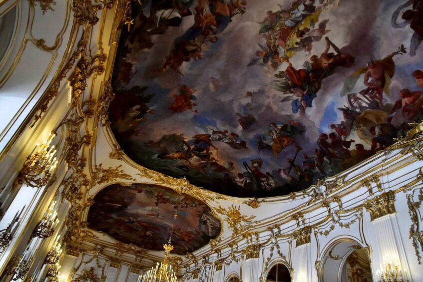 An ornate ceiling with intricate gold detailing and a large fresco. 5