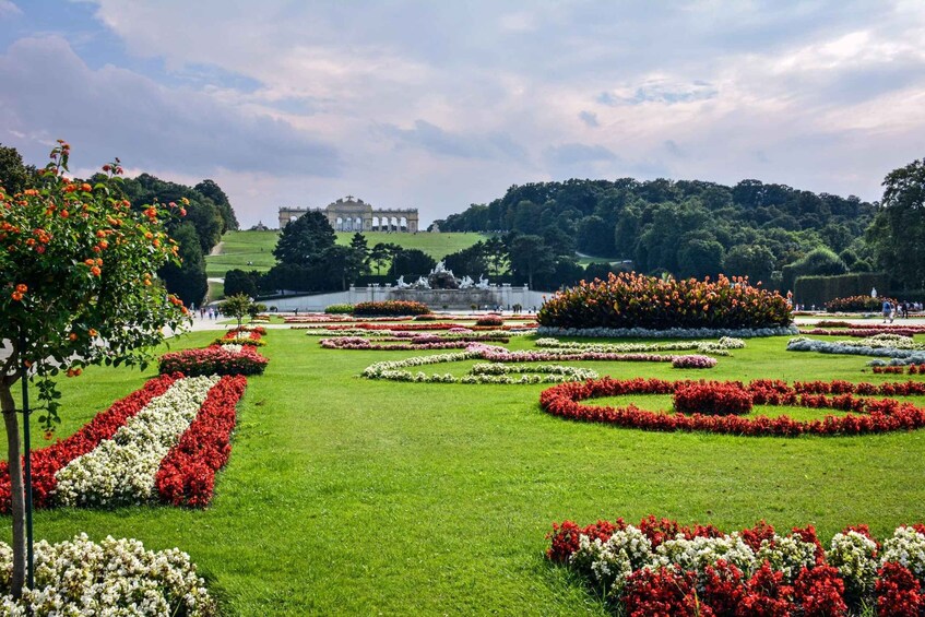 A well-manicured garden with geometric flower beds and a large building in the background. 3