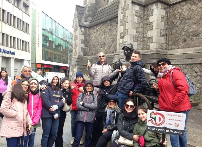 A group of people posing in front of a statue and a building. 2