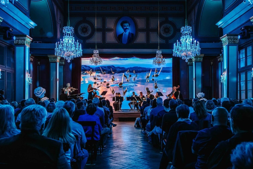 A classical music concert in a grand hall with chandeliers and a large audience. 1