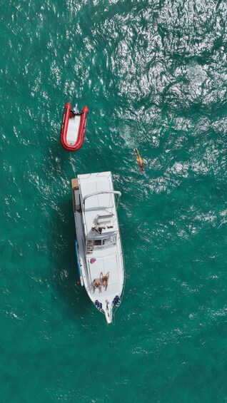 A boat with two people on deck and a red inflatable raft in the water. 5