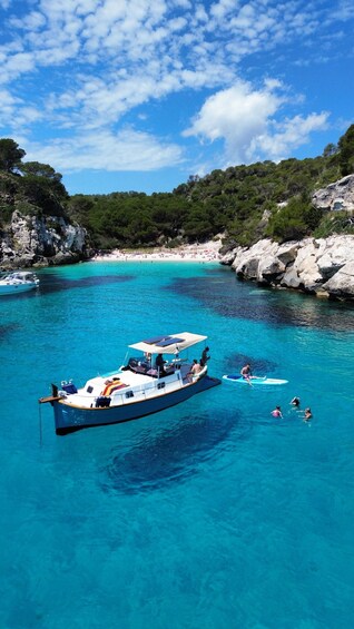 A boat with people on a clear blue sea, surrounded by rocky cliffs and greenery. 4