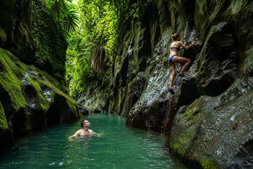 Una persona arrampica una parete rocciosa ricoperta di muschio in un ambiente naturale acquatico. 5