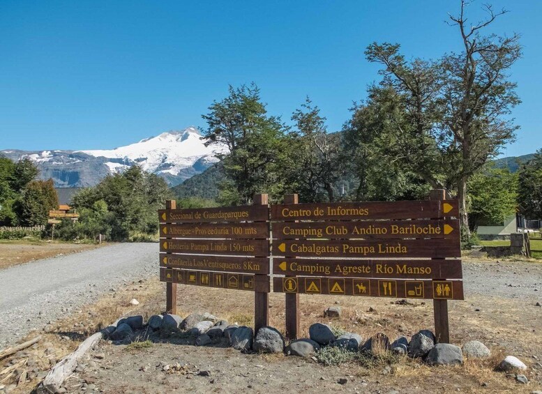A directional signpost with multiple arrows pointing to various destinations including a camping club and a mountain range. 4