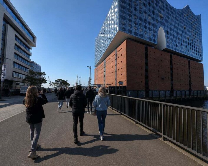 A pedestrian walkway with a modern building featuring a unique facade with circular patterns. 4