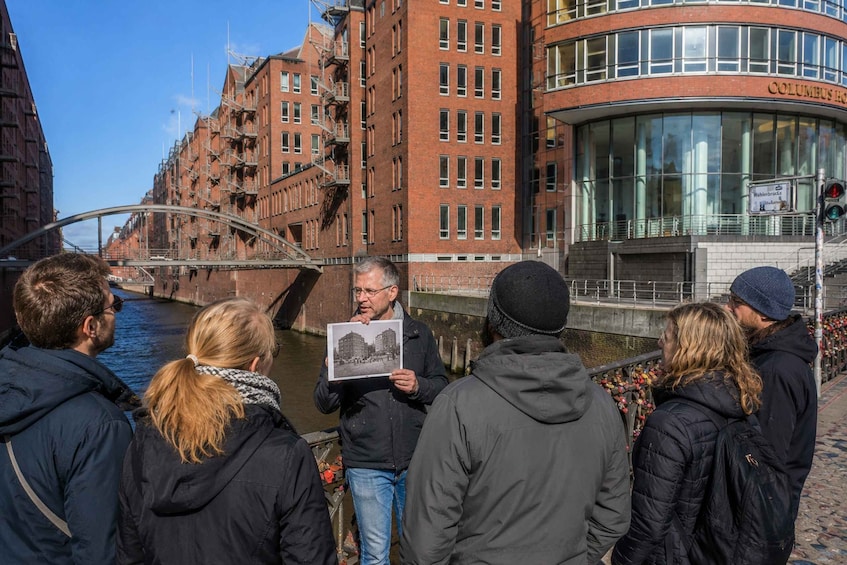 A group of people standing by a canal with buildings in the background. 3