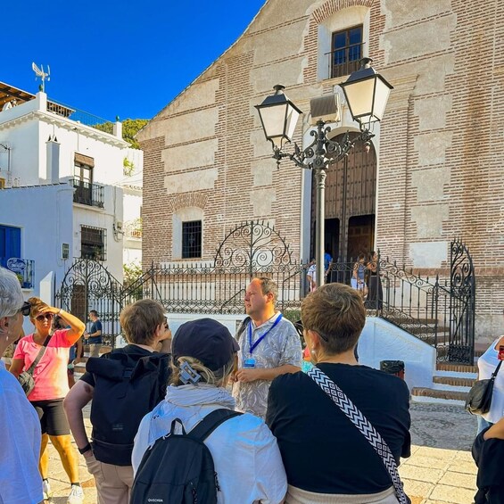 Un grupo de personas de pie frente a un edificio histórico con una reja de hierro forjado y un farol. 3