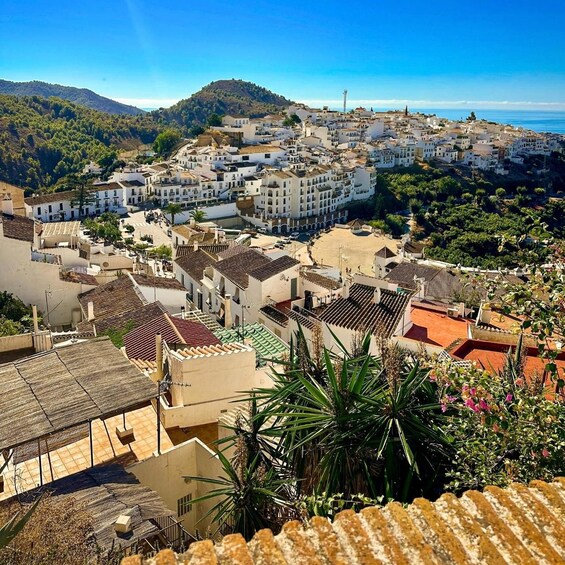 A coastal town with white buildings, terracotta roofs, and a mountainous backdrop. 5