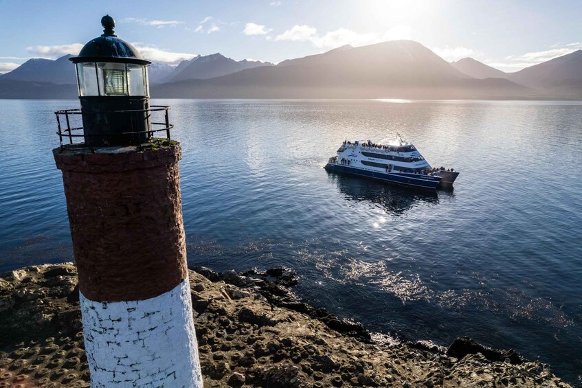 A lighthouse and a boat on a calm lake with mountains in the background. 4