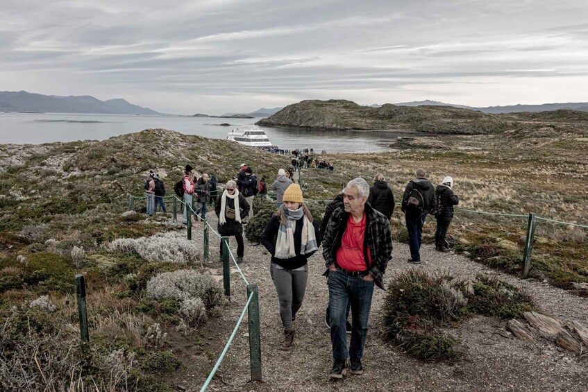 A group of people walking on a trail with a boat in the background. 2