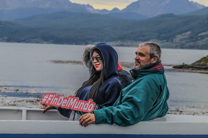 Two people sitting on a boat with a lake and mountains in the background. 1
