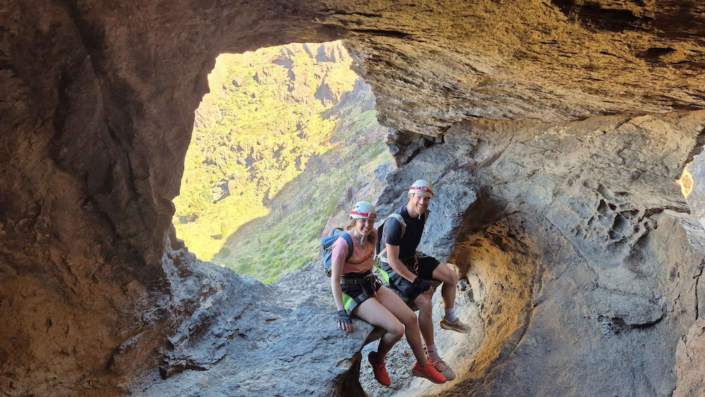 Two people climbing a rocky cliff with a canyon in the background. 4