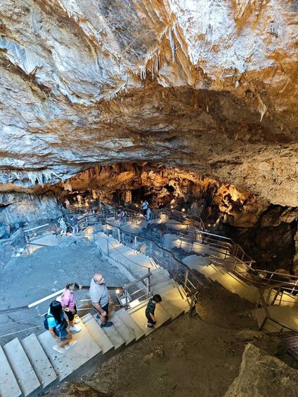 En hule med stalaktitter og stalagmitter, en trappe der fører ned i hulen, og folk der udforsker den. 3