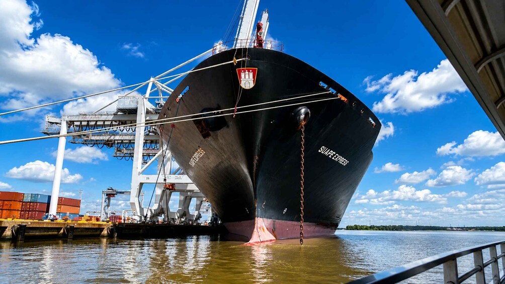 A large ship docked at a port with cranes and containers in the background. 3