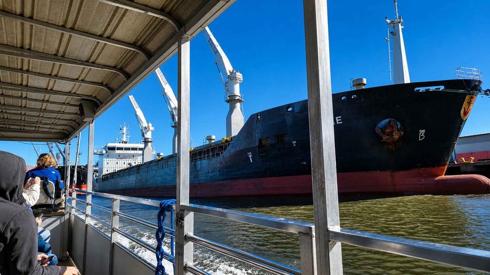 A large ship docked at a port with people on a nearby boat. 5