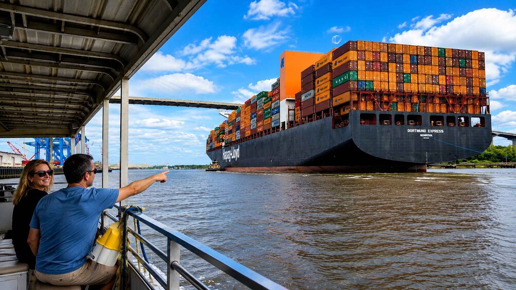 A large cargo ship named 'Dortmund Express' docked under a bridge, with a person pointing towards it. 4