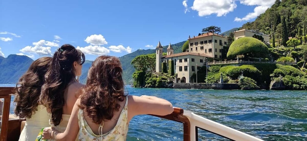 Two people on a boat, a lake, and a castle-like building on a hill. 1